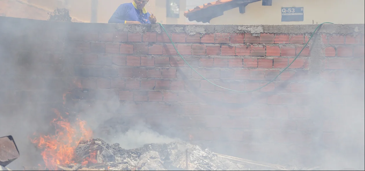 Morador tentando apagar o fogo com água da mangueira 